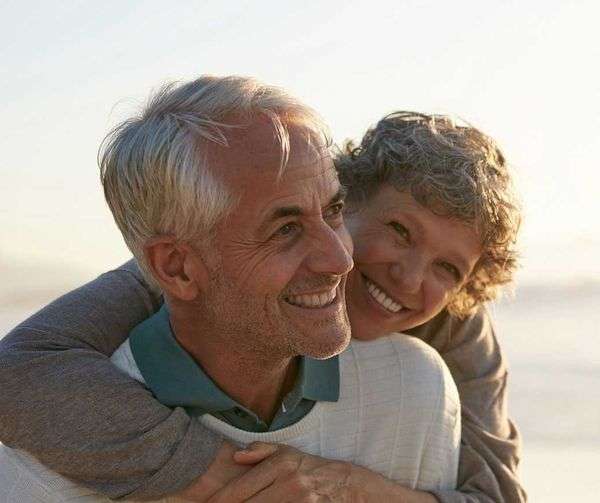 Happy retired couple walking down the beach